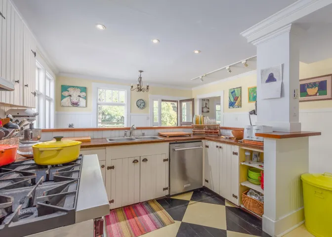 Kitchen with a sink, ornamental molding, a wainscoted wall, and dishwasher