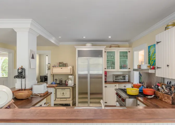 Kitchen featuring decorative columns, ornamental molding, recessed lighting, built in fridge, and a toaster