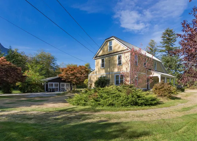 View of side of property featuring a yard and an outbuilding