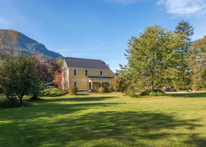 Rear view of property featuring a yard, a mountain view, and covered porch
