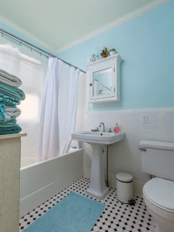 Bathroom with toilet, wainscoting, shower / bath combo with shower curtain, and ornamental molding
