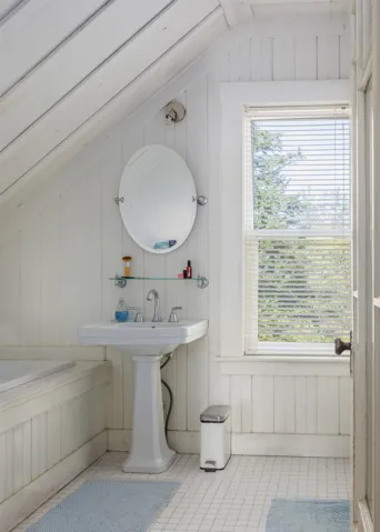 Bathroom featuring wood walls, vaulted ceiling, and a healthy amount of sunlight