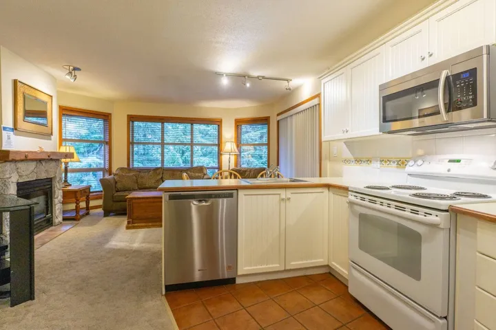 Kitchen with stainless steel appliances, dark tile patterned floors, a peninsula, white cabinets, and open floor plan