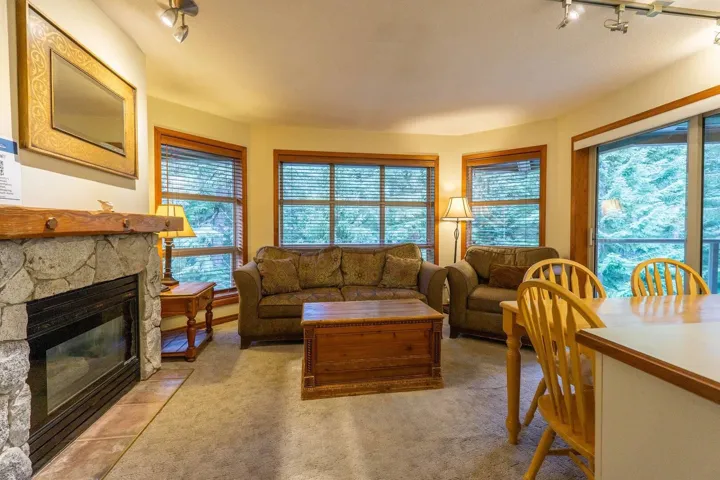 Living room with rail lighting, a stone fireplace, and light colored carpet