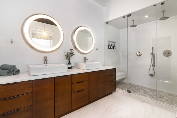 Bathroom with double vanity, light marble finish flooring, and a stall shower