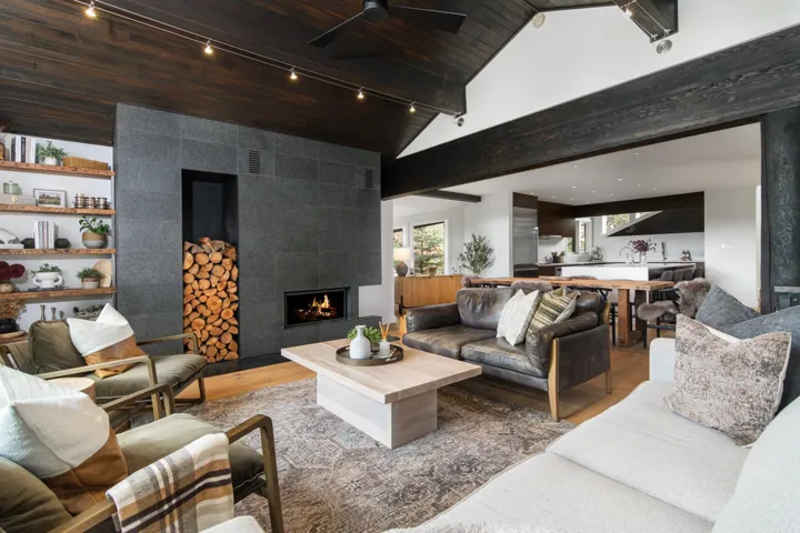 Living room featuring wood finished floors, a ceiling fan, rail lighting, a tiled fireplace, and a wood ceiling with exposed beams