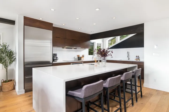 Kitchen with decorative backsplash, dark brown cabinets, a kitchen breakfast bar, built in fridge, and recessed lighting