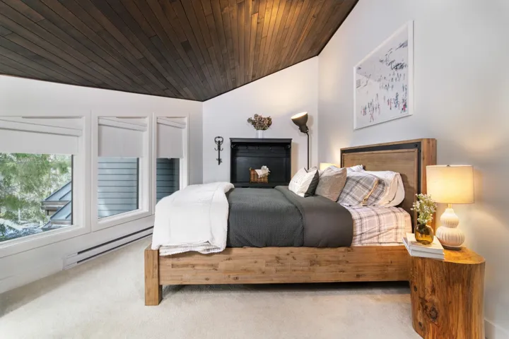 Carpeted bedroom with baseboard heating, vaulted ceiling, and wooden ceiling