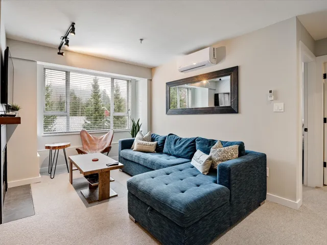 Carpeted living room with an AC wall unit, baseboards, and rail lighting