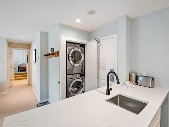 Laundry area with laundry area, recessed lighting, light carpet, a sink, and stacked washer / drying machine