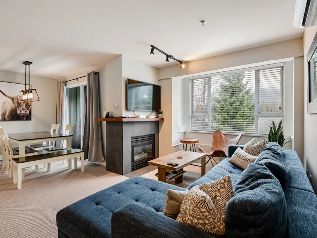Living room featuring track lighting, carpet flooring, a fireplace, and an AC wall unit