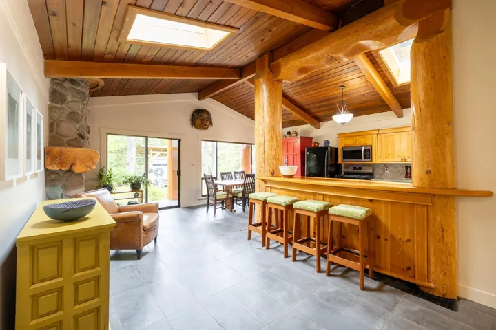 Kitchen featuring wooden ceiling, a kitchen breakfast bar, backsplash, appliances with stainless steel finishes, and vaulted ceiling with skylight
