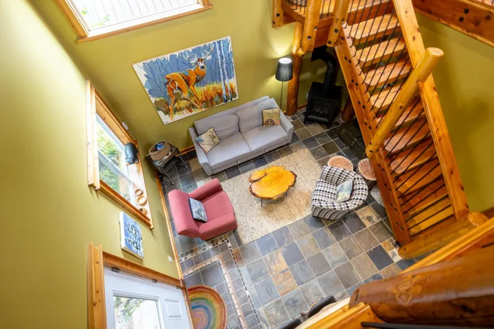Living room featuring a wood stove, stairs, a high ceiling, and stone tile floors