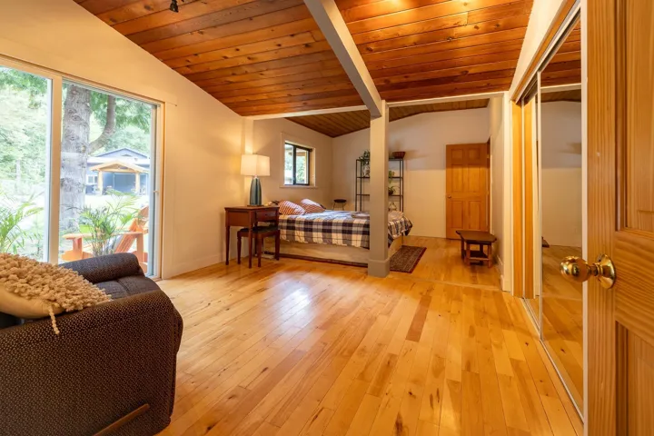 Bedroom featuring light wood-style floors, wood ceiling, and vaulted ceiling with beams
