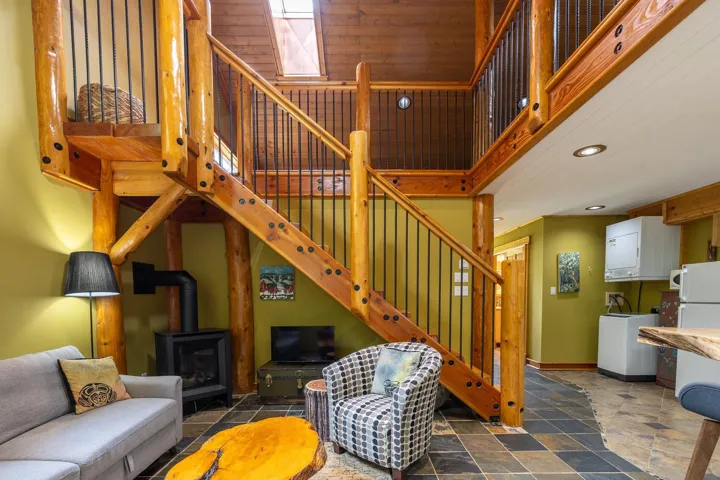 Living room featuring recessed lighting, stone tile floors, baseboards, stairs, and a wood stove