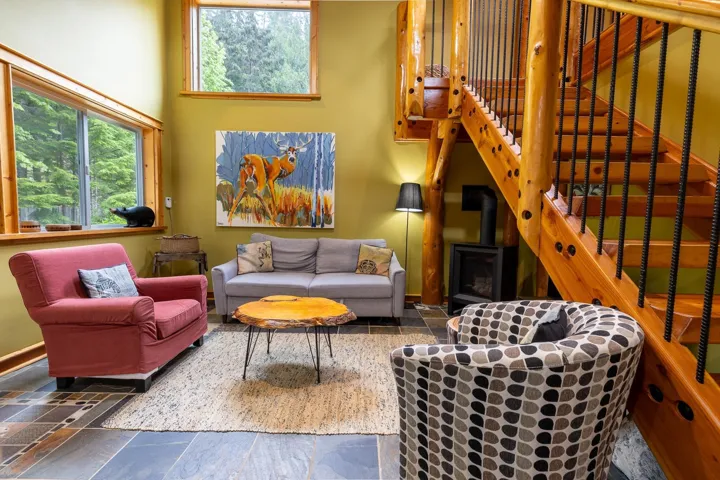 Living area with a wood stove, a towering ceiling, a healthy amount of sunlight, and stone tile flooring