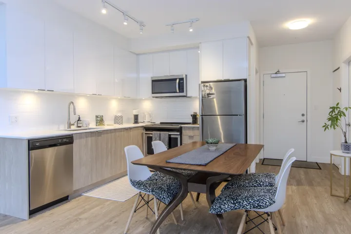 Kitchen featuring modern cabinets, appliances with stainless steel finishes, white cabinetry, light wood finished floors, and backsplash