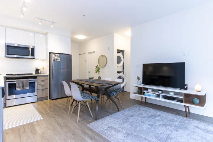 Dining area featuring light wood finished floors, estacked washer and dryer, and track lighting