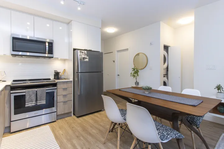 Kitchen featuring appliances with stainless steel finishes, tasteful backsplash, modern cabinets, white cabinetry, and light wood finished floors