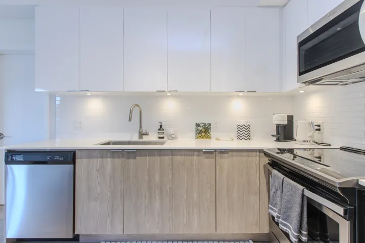 Kitchen featuring appliances with stainless steel finishes, modern cabinets, tasteful backsplash, and white cabinetry