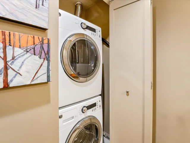 Clothes washing area with stacked washing maching and dryer and laundry area