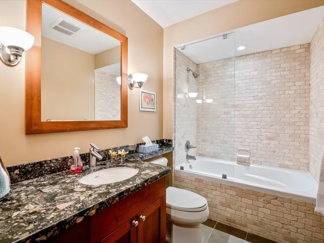 Full bath with tile patterned floors, toilet, tiled shower / bath combo, vanity, and visible vents