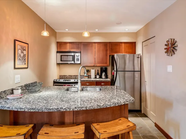 Kitchen featuring a kitchen breakfast bar, decorative light fixtures, stainless steel appliances, a sink, and a peninsula