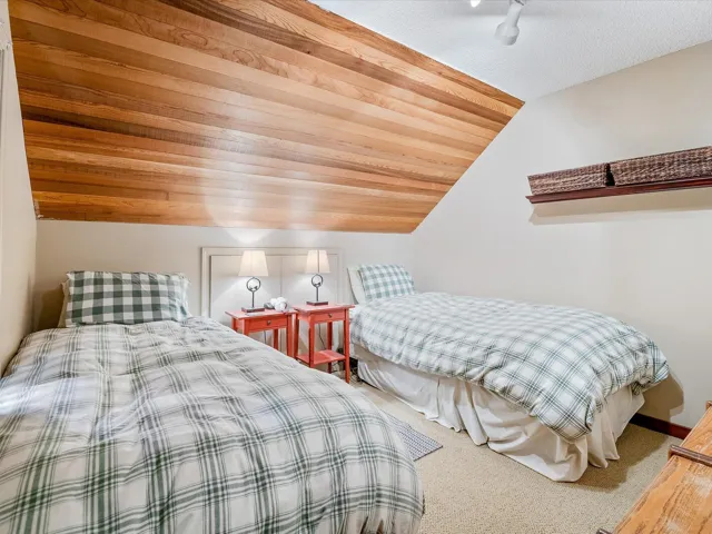 Carpeted bedroom featuring lofted ceiling, wooden ceiling, and rail lighting