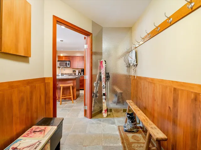 Hall with a wainscoted wall, wooden walls, stone finish flooring, and a sink