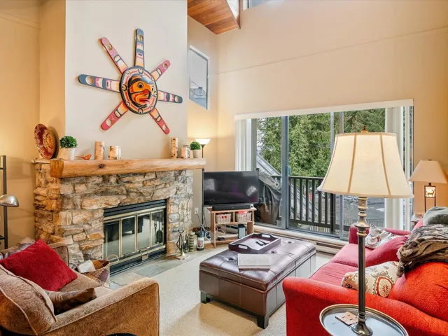 Living area with a high ceiling and a stone fireplace