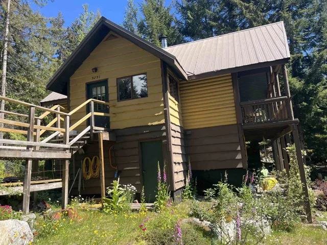 Two-story cabin featuring a metal roof and an elevated deck with wood railings