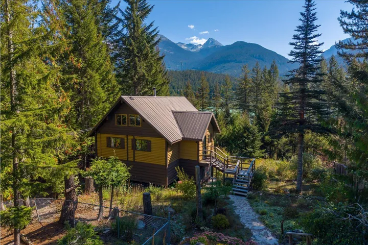 Wood-sided cabin featuring a metal roof, elevated deck, and a stone pathway