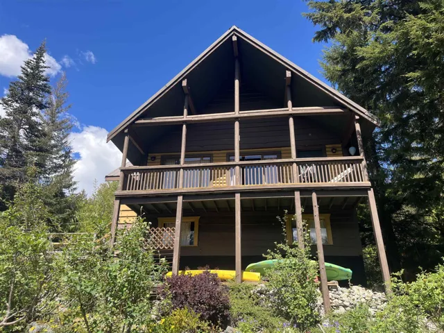 Wood-sided multi-level cabin featuring a prominent A-frame roofline and two outdoor covered deck areas