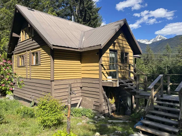 Cabin-style residence featuring a metal roof, log-style siding, and multi-level wooden decking