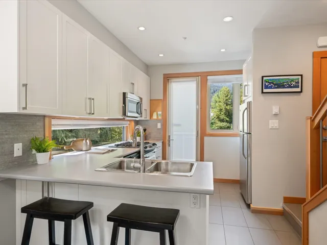 Kitchen featuring healthy amount of natural light, a peninsula, a breakfast bar area, light countertops, and recessed lighting