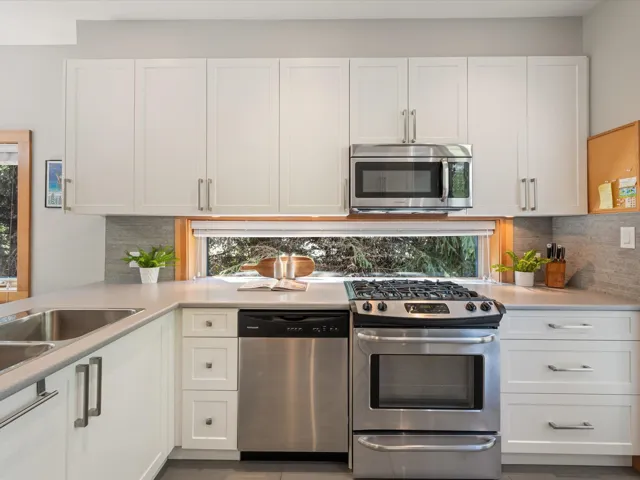 Kitchen featuring appliances with stainless steel finishes, white cabinets, tasteful backsplash, and light countertops