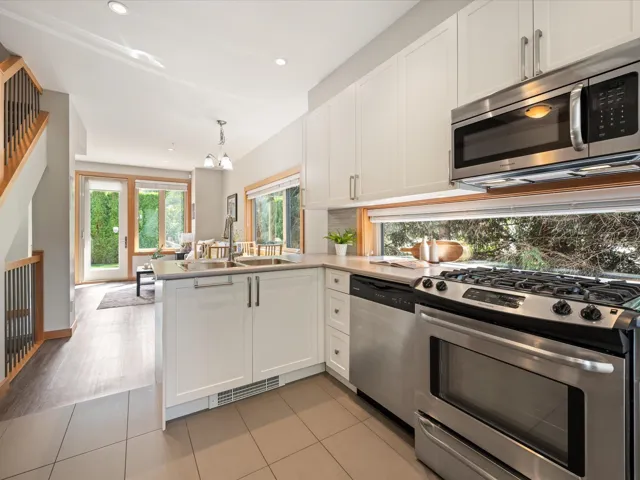 Kitchen featuring appliances with stainless steel finishes, white cabinets, light tile patterned floors, hanging light fixtures, and recessed lighting