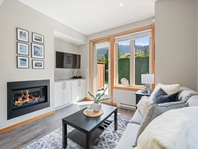 Living room with a glass covered fireplace, wood finished floors, and baseboard heating