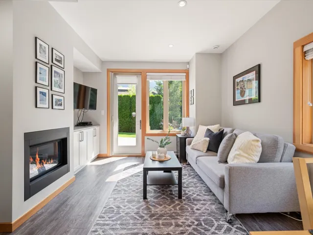 Living room with a glass covered fireplace, dark wood-style floors, and recessed lighting