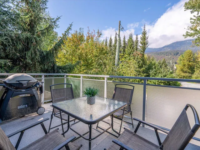 Balcony featuring outdoor dining space, grilling area, a view of trees, and a mountain view