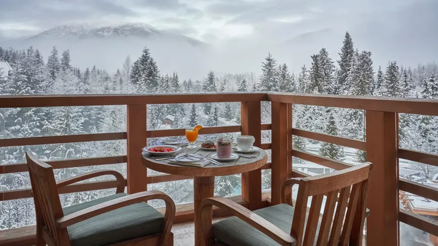 Snow covered back of property featuring a mountain view and a forest view