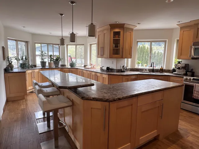 Spacious kitchen featuring light wood cabinetry and dark patterned countertops