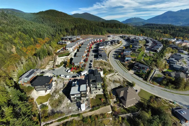 Aerial view of property and surrounding area with a heavily wooded area and nearby suburban area