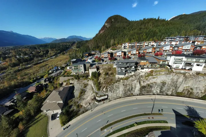 Aerial view of property and surrounding area featuring nearby suburban area and a mountain backdrop