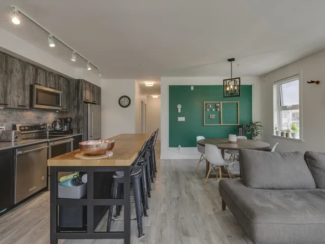 Kitchen featuring stainless steel appliances, rail lighting, tasteful backsplash, and light wood-style floors