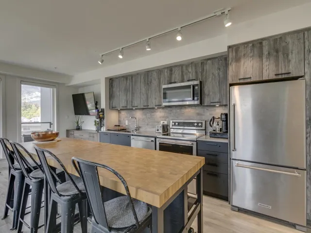 Kitchen with light countertops, tasteful backsplash, rail lighting, light wood-style flooring, and appliances with stainless steel finishes