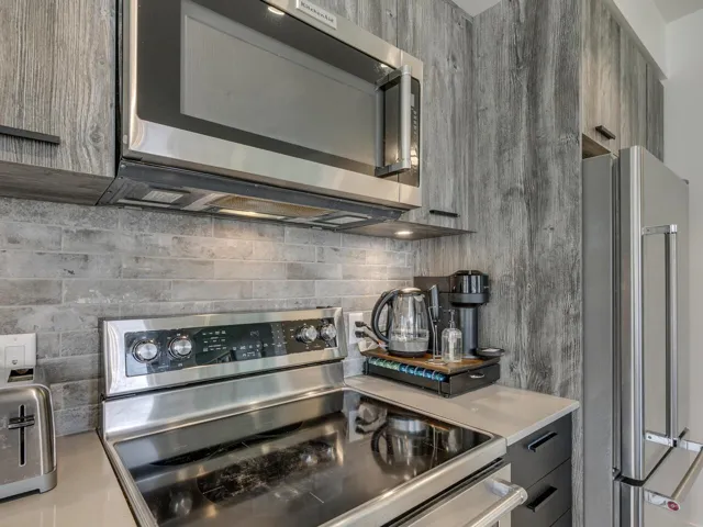 Kitchen with light countertops, backsplash, gray cabinetry, and stainless steel appliances