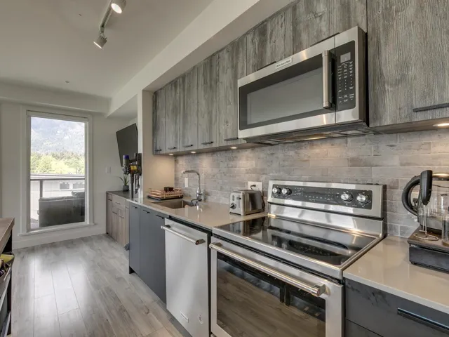 Kitchen featuring modern cabinets, light countertops, gray cabinets, a sink, and appliances with stainless steel finishes