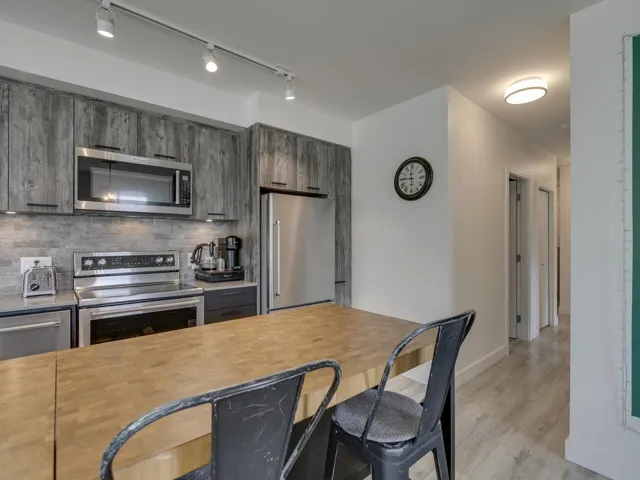 Kitchen featuring decorative backsplash, a breakfast bar, baseboards, light wood finished floors, and appliances with stainless steel finishes