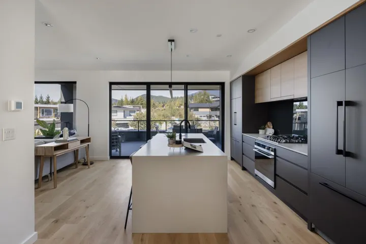 Kitchen with modern cabinets, a kitchen island with sink, gray cabinetry, stainless steel appliances, and light wood-style flooring